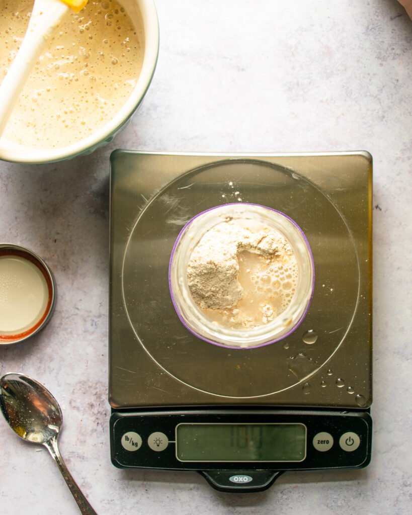 An overhead shot looking down at a mason jar on a scale with sourdough starter inside.