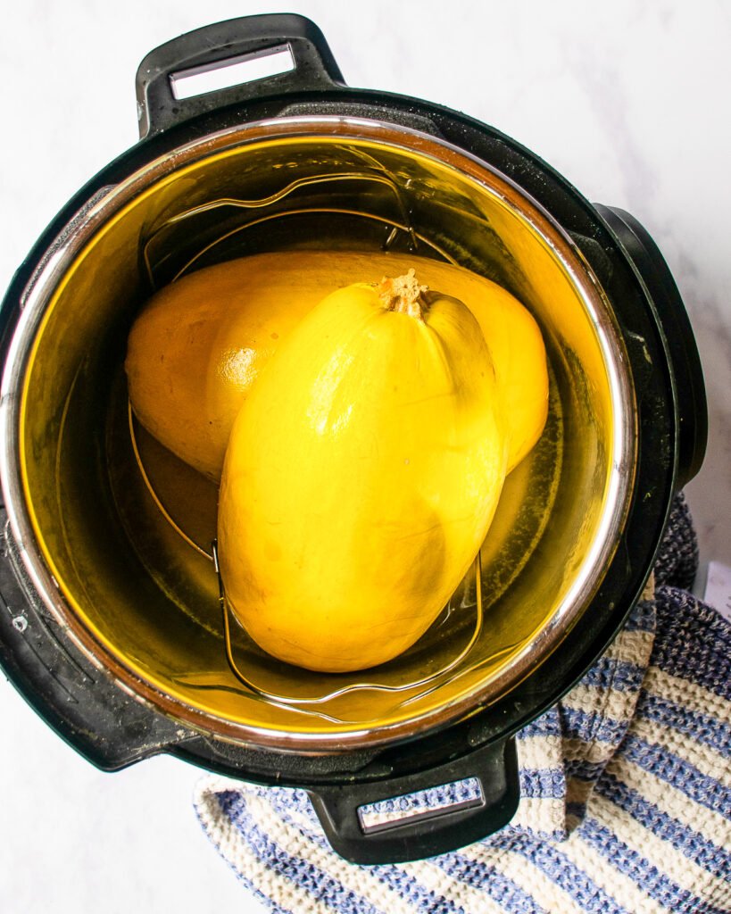Spaghetti squash cut in half and stacked in a pressure cooker.