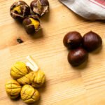 Raw, roasted and peeled chestnuts on butcher block counter.
