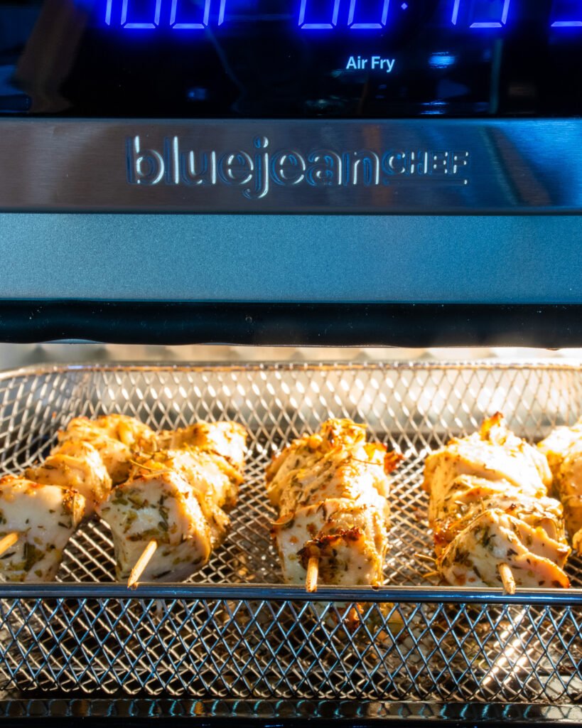 Chicken souvlaki skewers cooking in an air fryer oven.