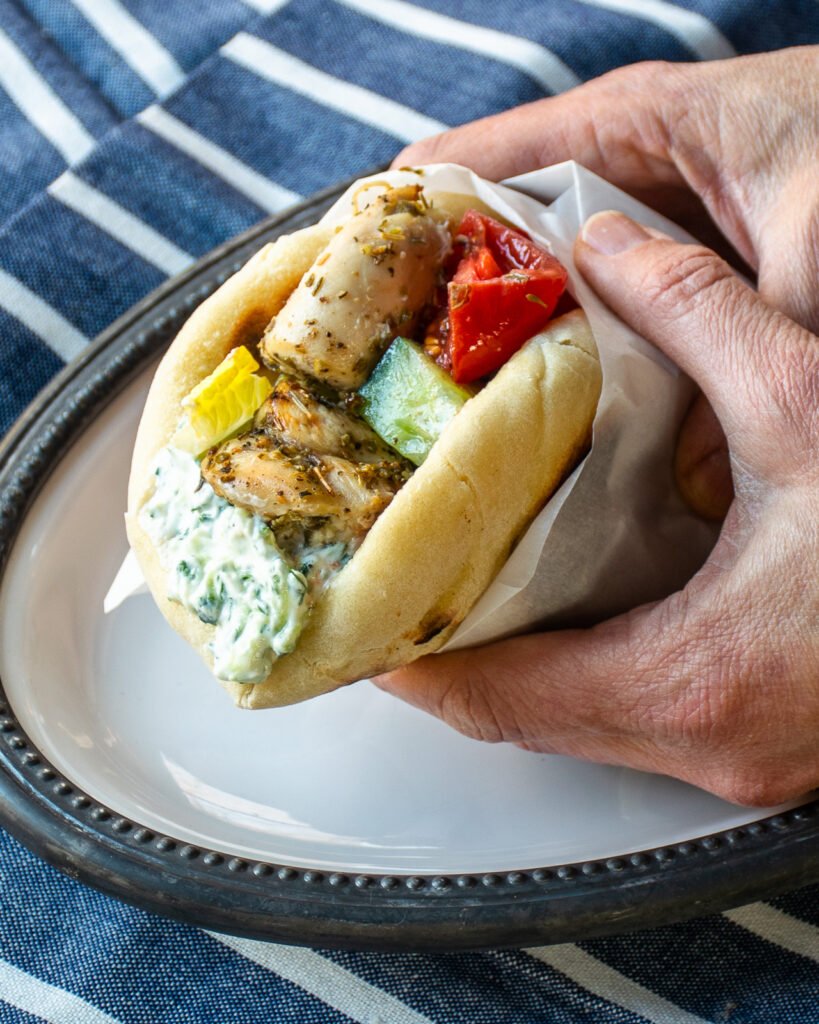 Chicken souvlaki rolled up in a pita bread with tzatziki sauce and tomato.