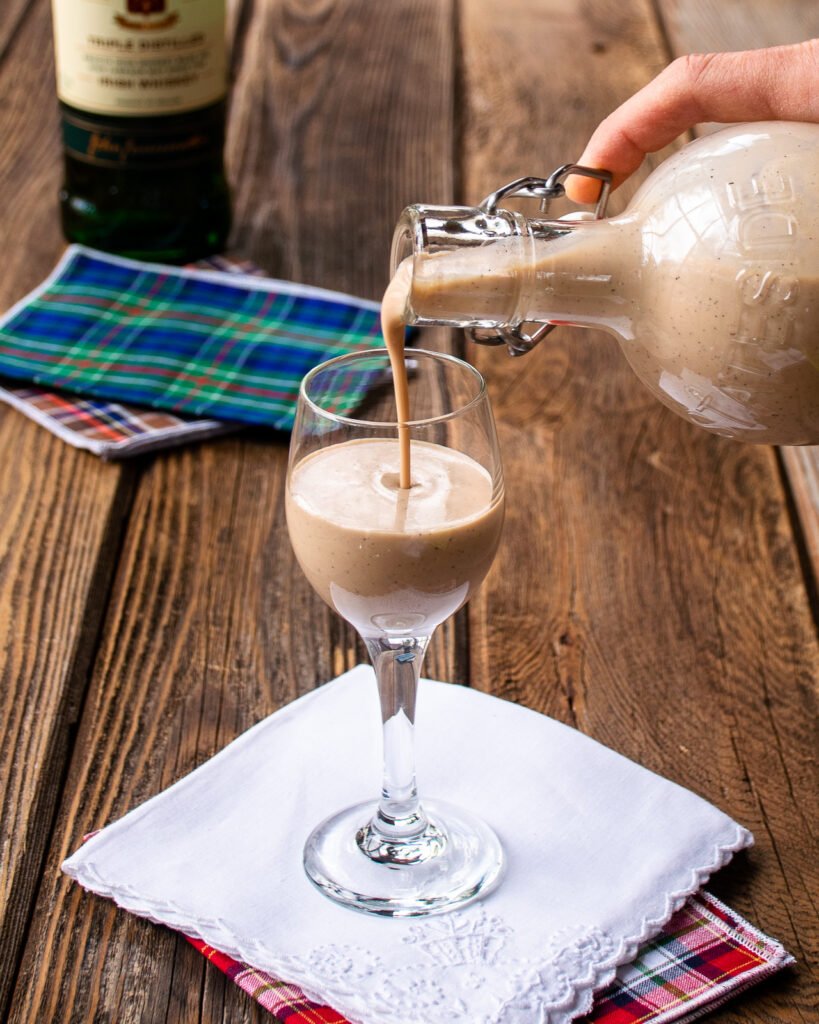 Pouring Irish cream into a digestive glass on a white napkin.