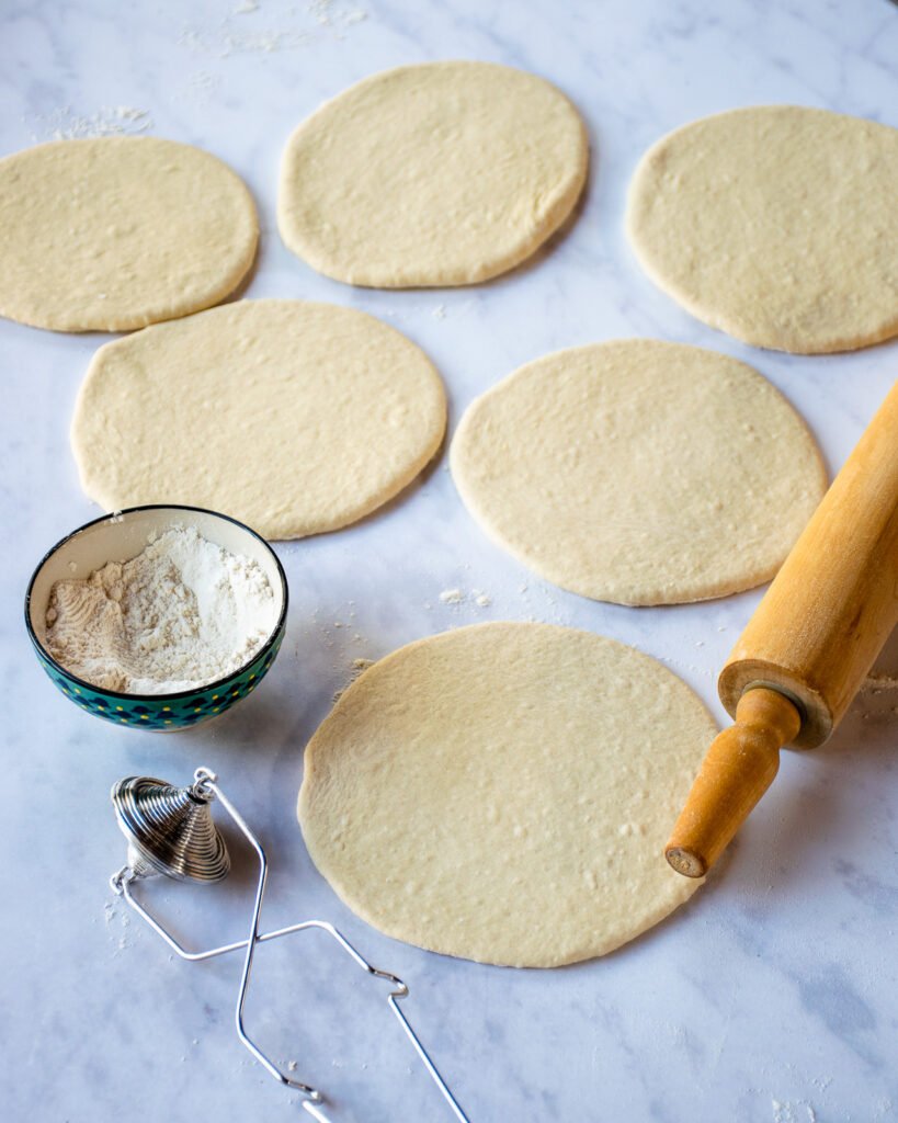 Pita bread dough rolled out on a coutertop.