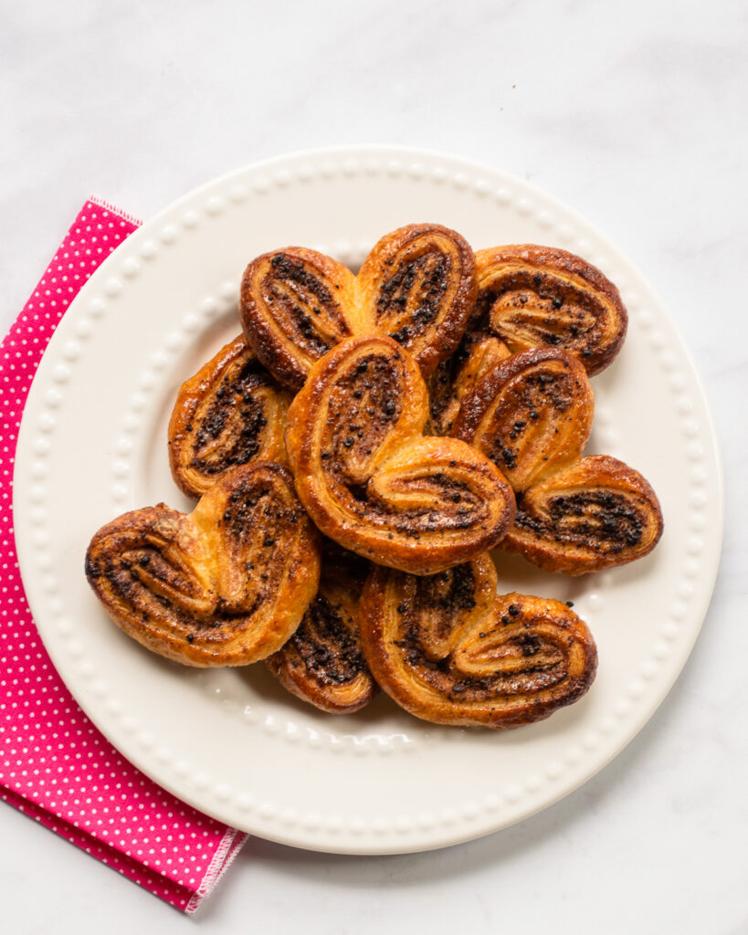 Chocolate palmiers on a white plate with a pink napkin.