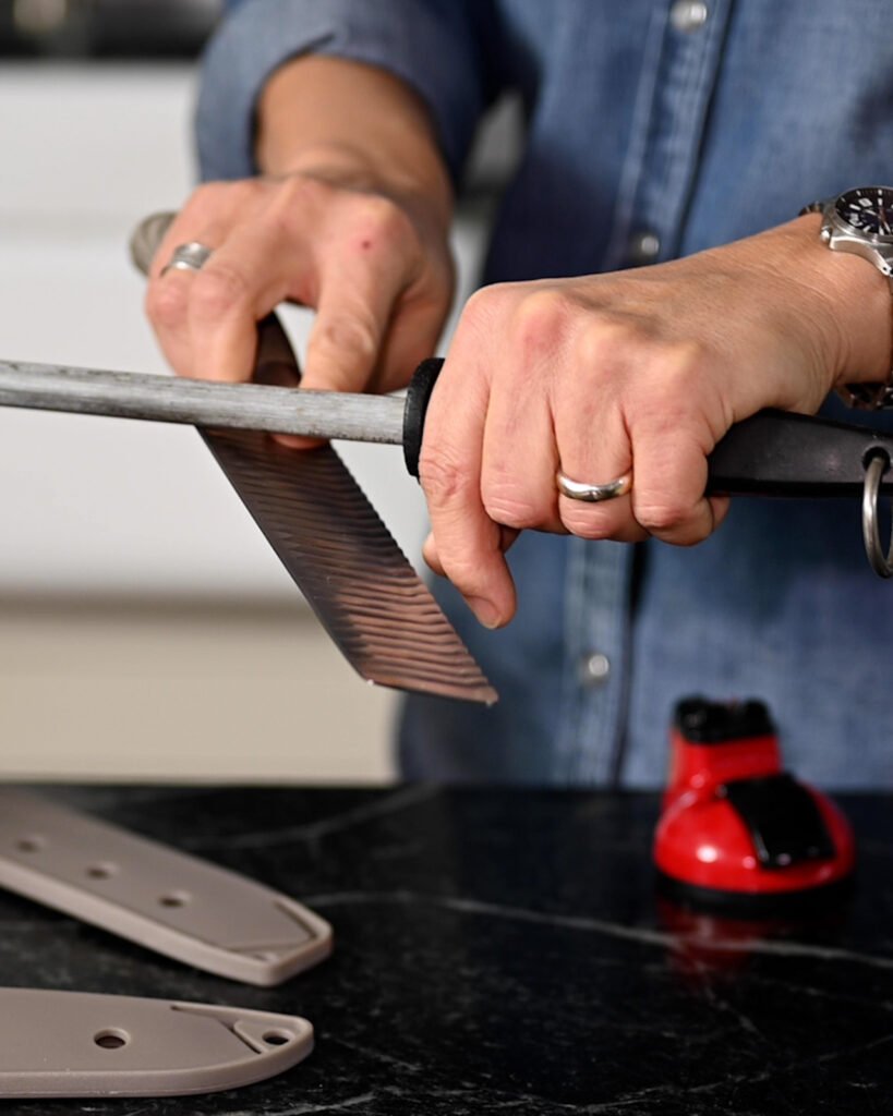 Hands running a nakiri knife along a honing steel.