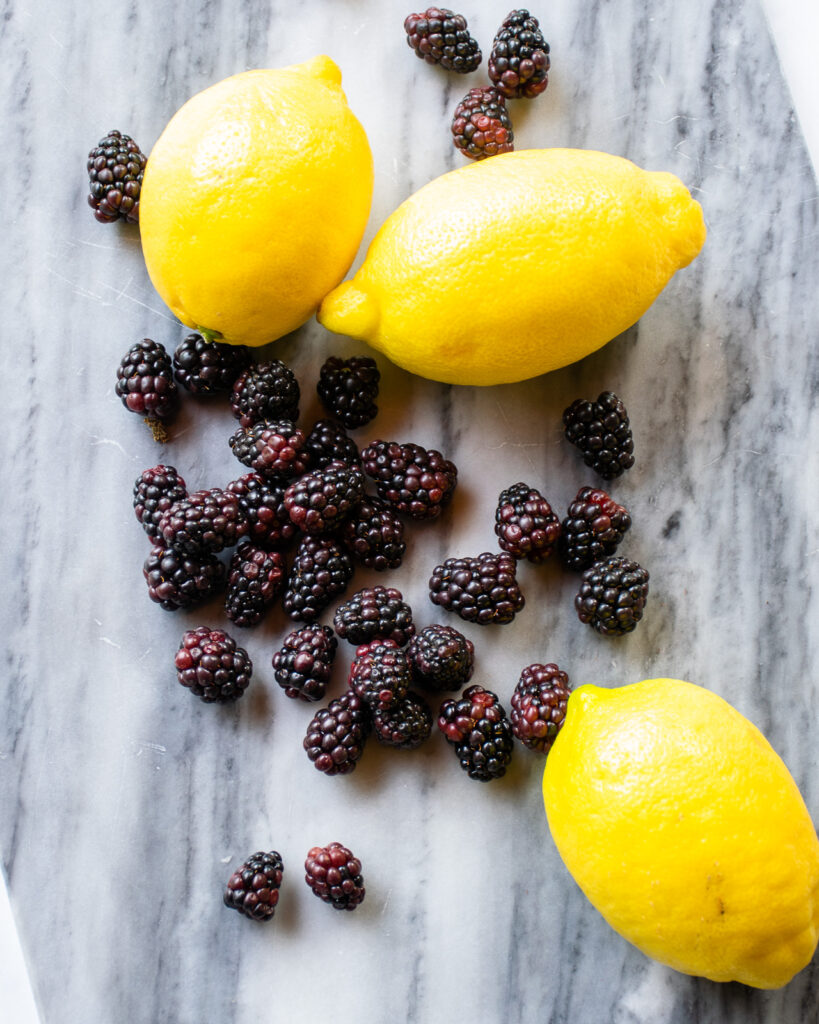 Lemons and blackberries on a marble surface.