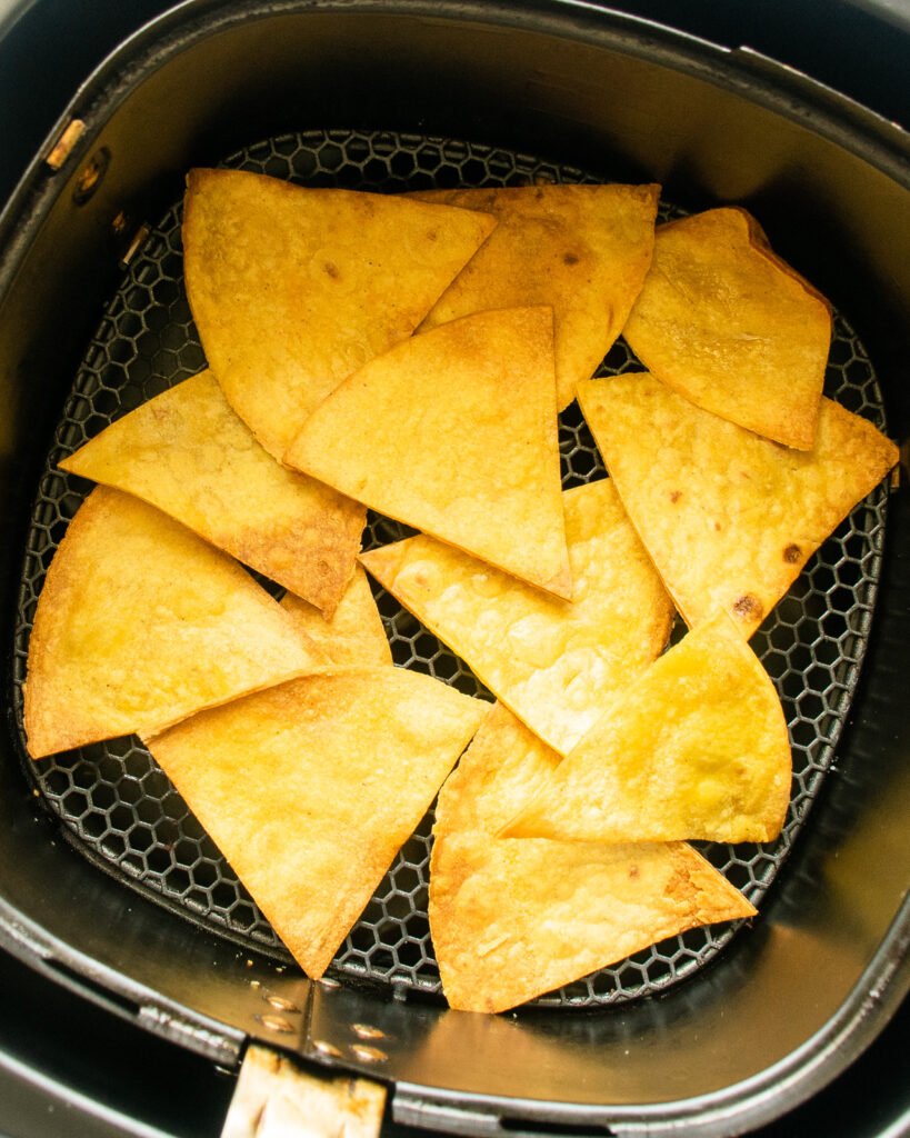 Air fryer tortilla chips in an air fryer basket.