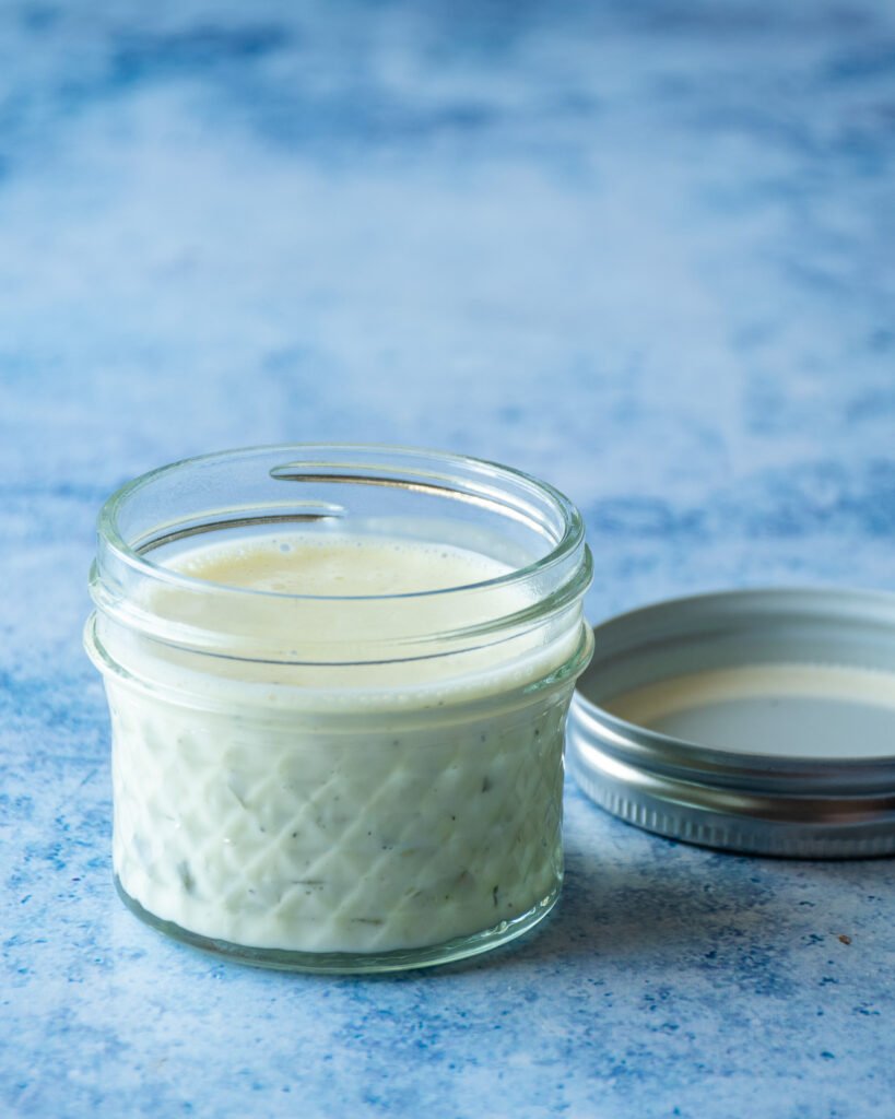 A small jar of tartar sauce on a blue countertop.