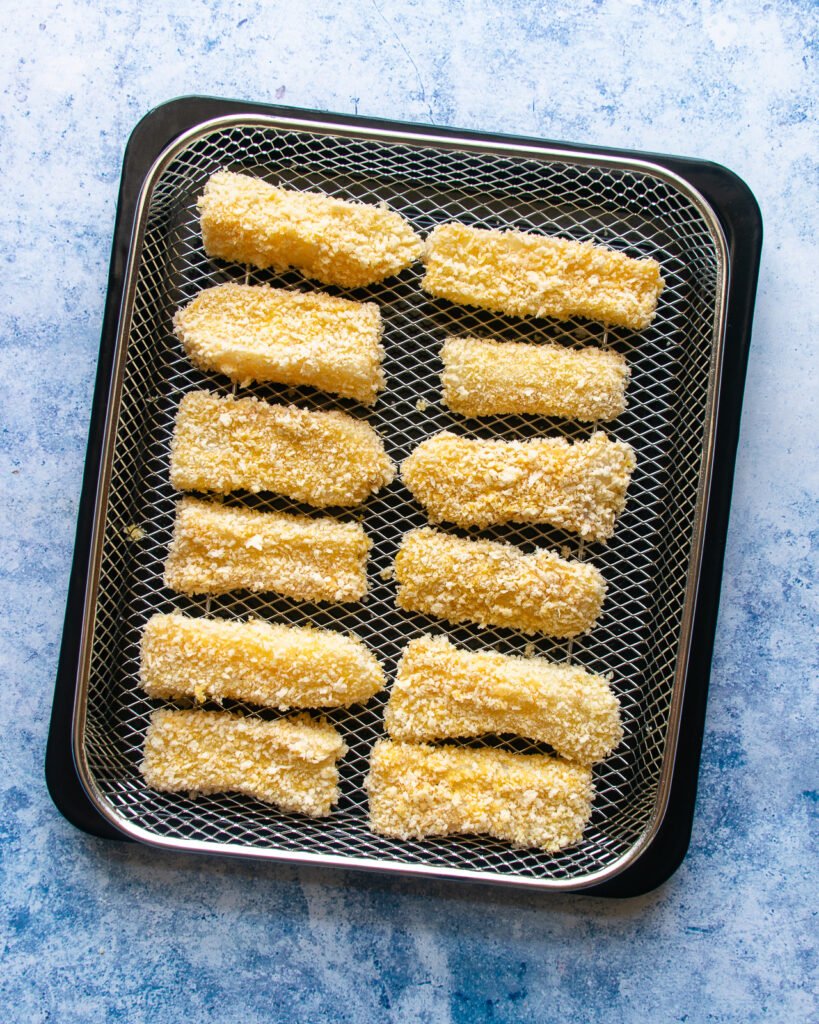 Breaded fish on an air fryer basket, ready to cook.