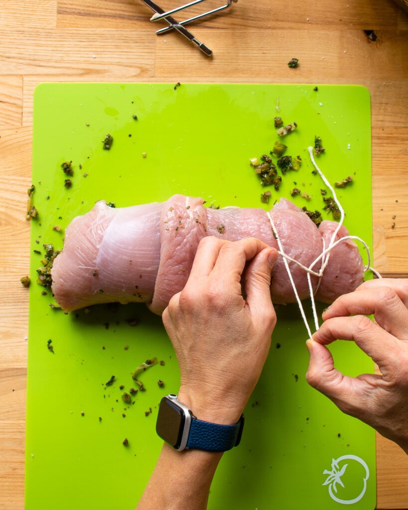 Hands showing how to tie up a turkey roulade.