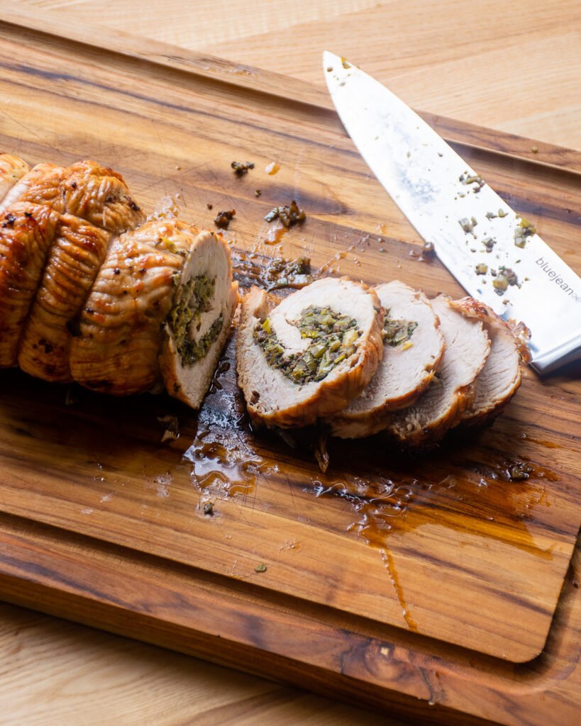 Slicing the turkey roulade on a cutting board.
