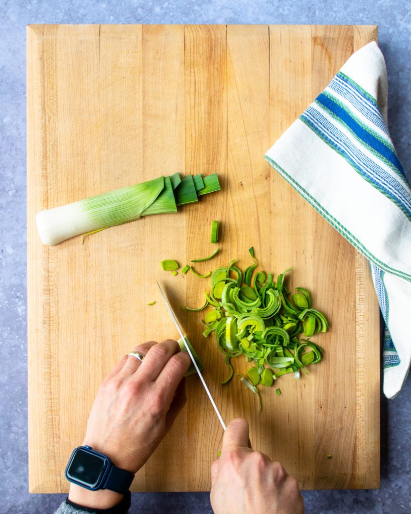 Hands slicing a leek.
