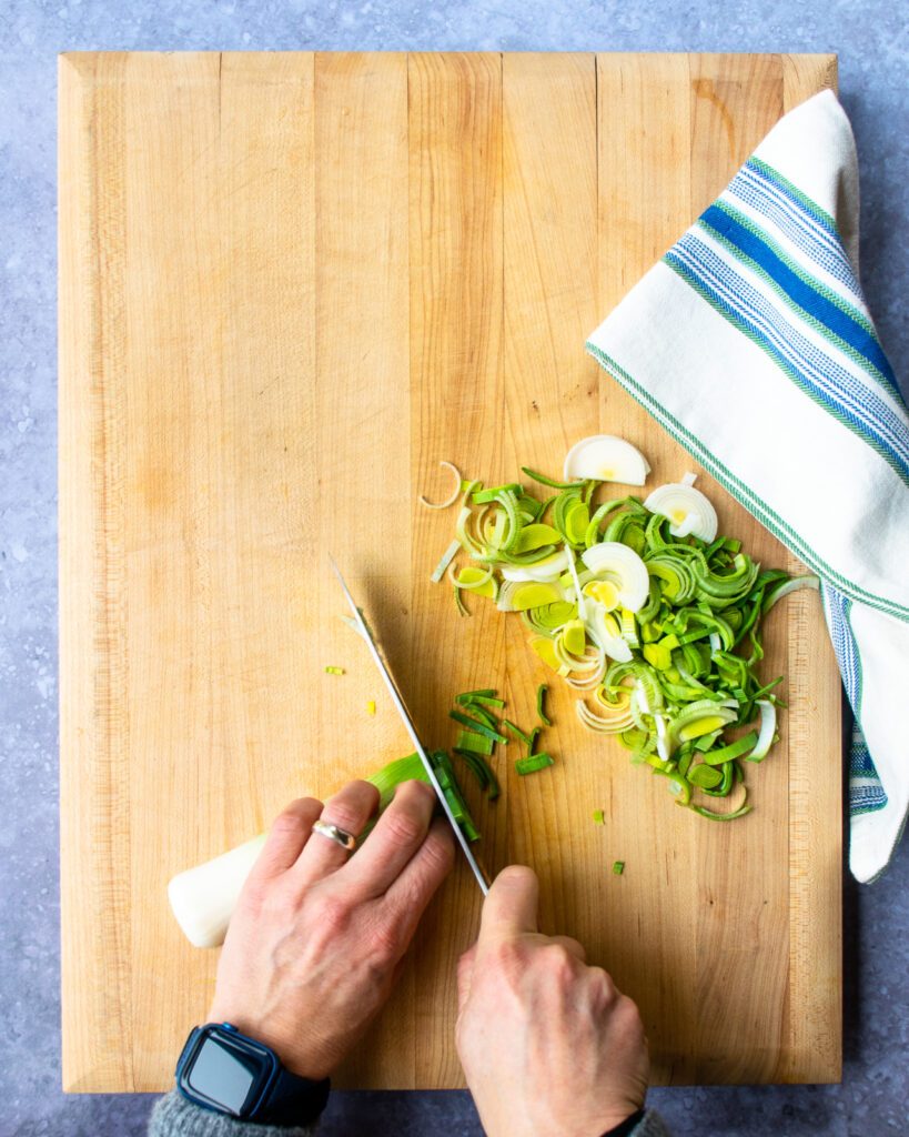 Hands slicing a leek.