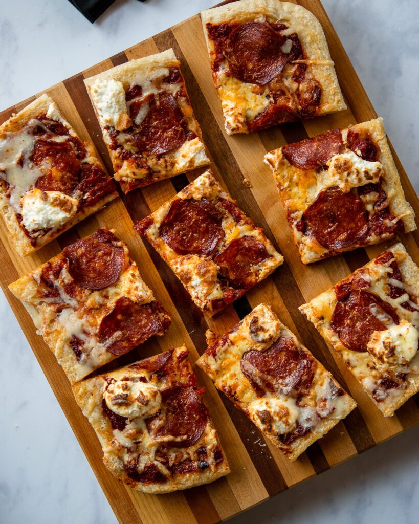 Looking down on an air fryer pan pizza cut into 9 pieces on a cutting board.