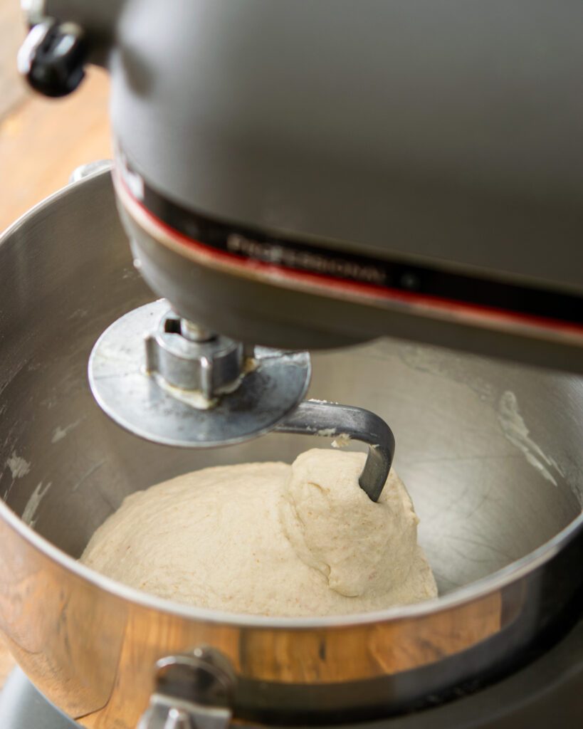 Looking into the bowl of a stand mixer with dough inside.