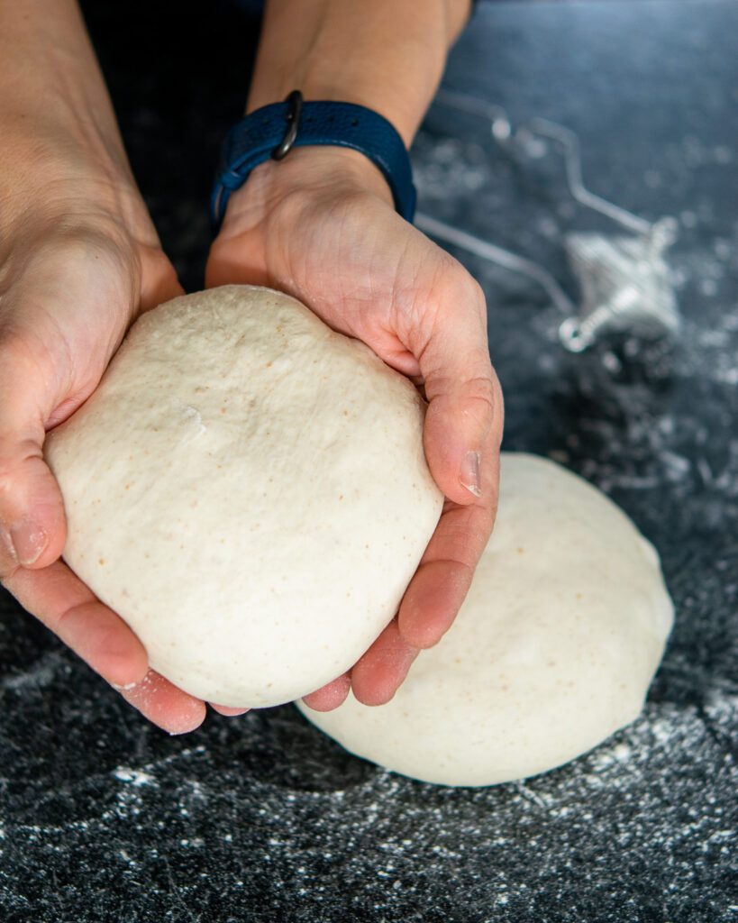Hands holding a ball of dough above a countertop.