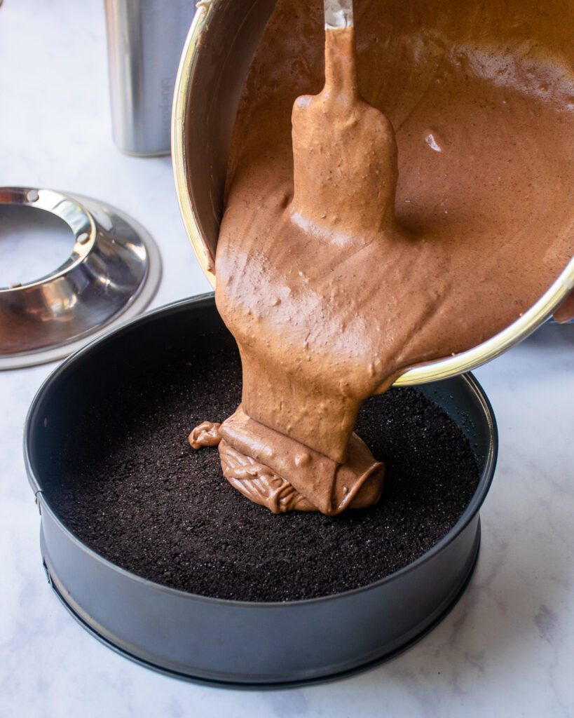 Pouring cheesecake batter into a springform pan.