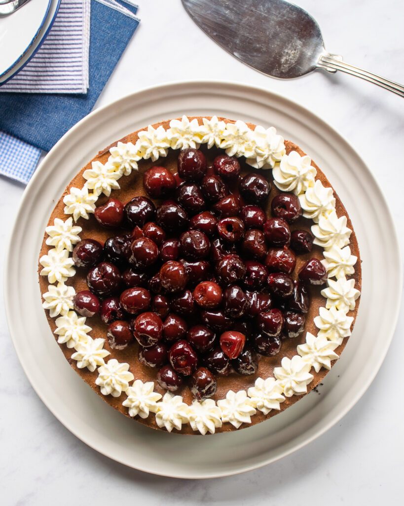 Looking down on a black forest cheesecake with a cake server and some napkins near by.