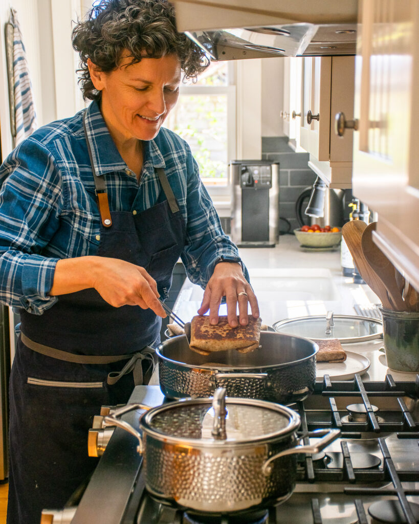 A woman flipping a burrito pocket in a saute pan.