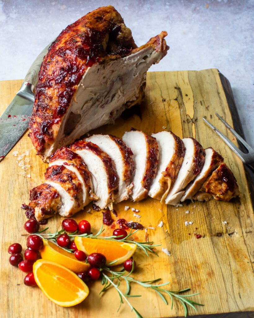 Roast turkey breast on a cutting board - one half on the bone and the other half carved.