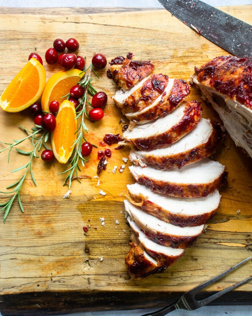 Looking down on sliced turkey breast on a cutting board.