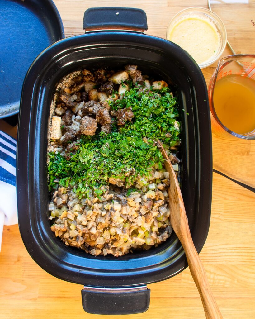 Looking straight down into a slow cooker with stuffing ingredients inside.