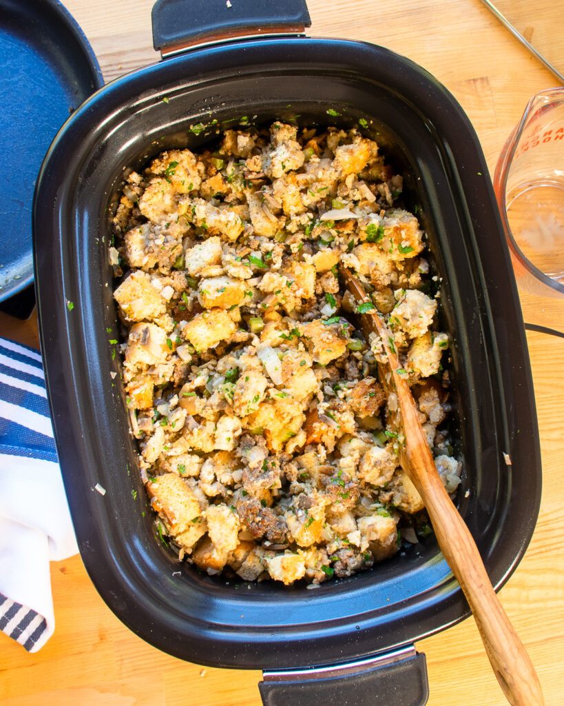 Looking straight down into a slow cooker with mixed up raw stuffing inside.