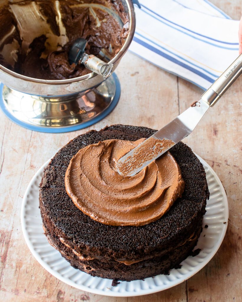 Icing a cake layer with an offset spatula.
