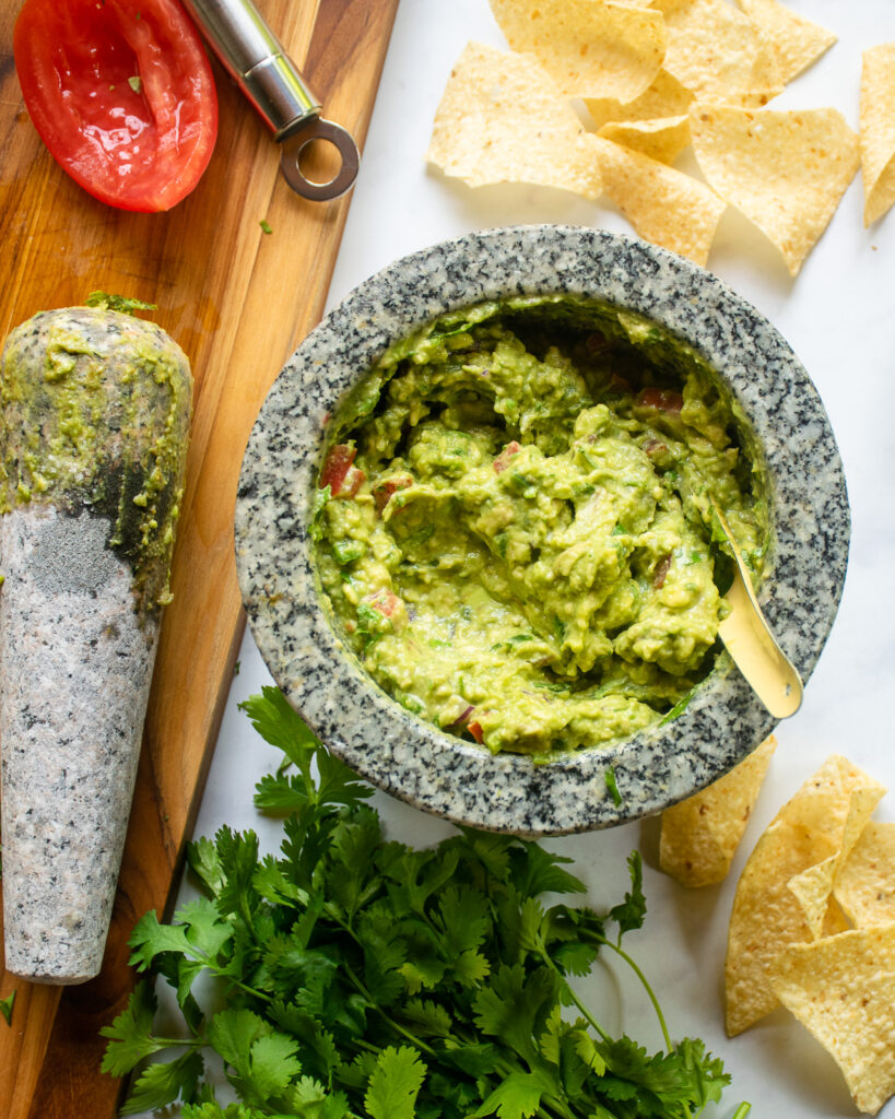 Looking down into a mortar of guacamole with chips near by.