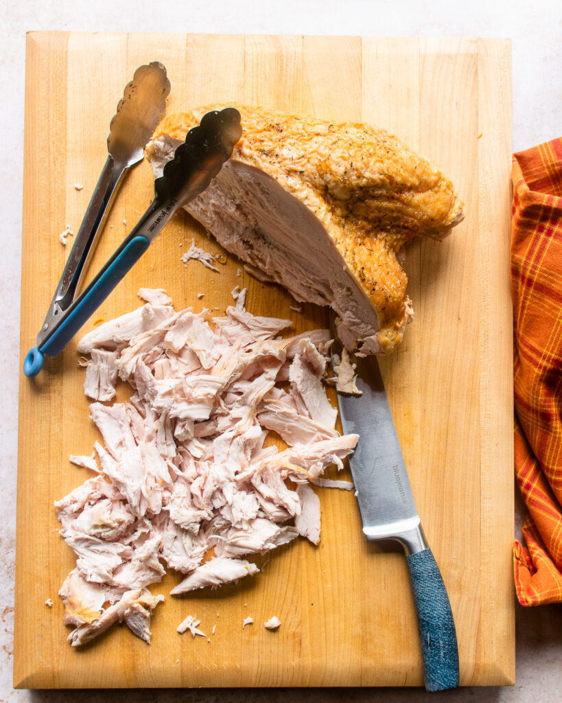 Shredded turkey on a wooden cutting board.