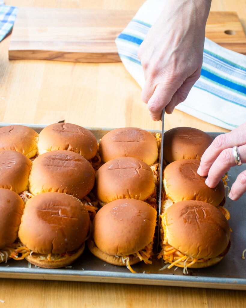 Hands cutting spaghetti sliders apart.
